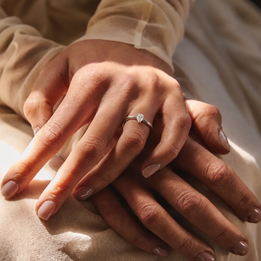 Two hands together, a RAUSCHMAYER engagement ring in detail